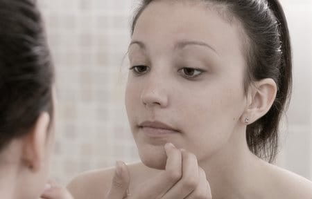 Woman touching her chin looking into a mirror