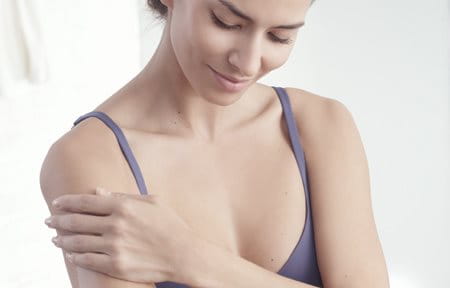 Woman applying cream on her body